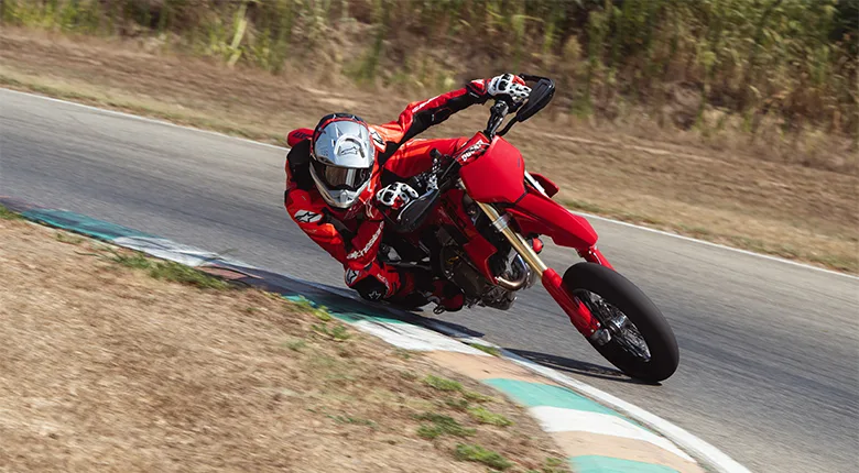 Rider cornering a red Ducati Desmo450 SM on a paved supermoto circuit.