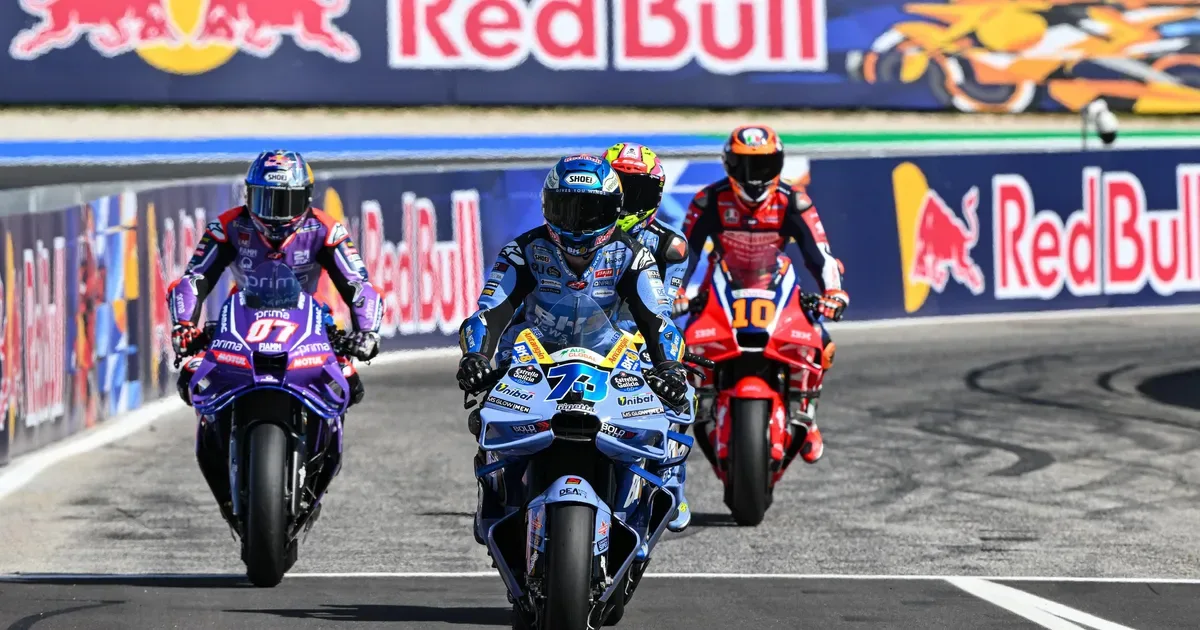 MotoGP riders and teams operating in a circuit pit-lane environment.