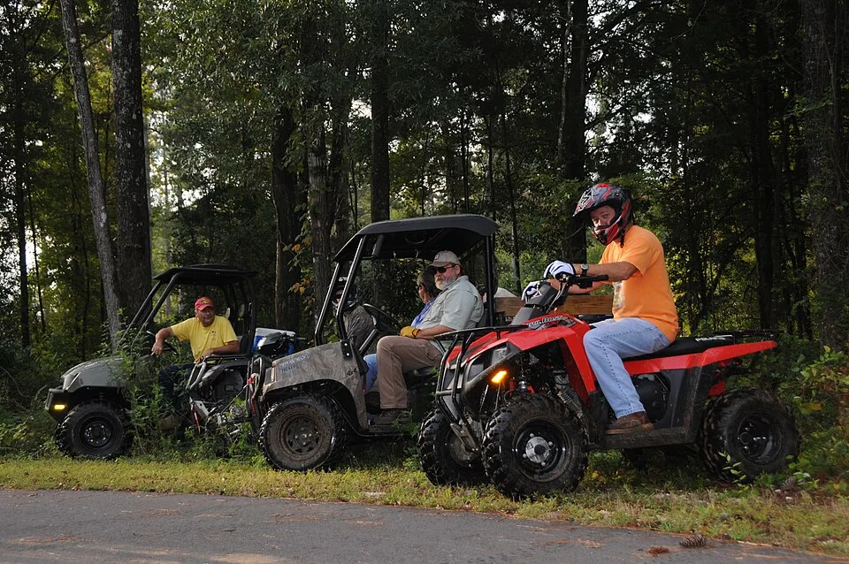 ATV riders travelling through a wooded trail during an organized trail ride.