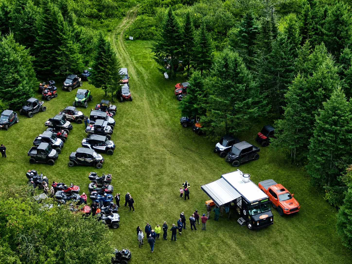 ATVs and side-by-sides gathered along a wooded PEI trail during a Dirt Road Rally event