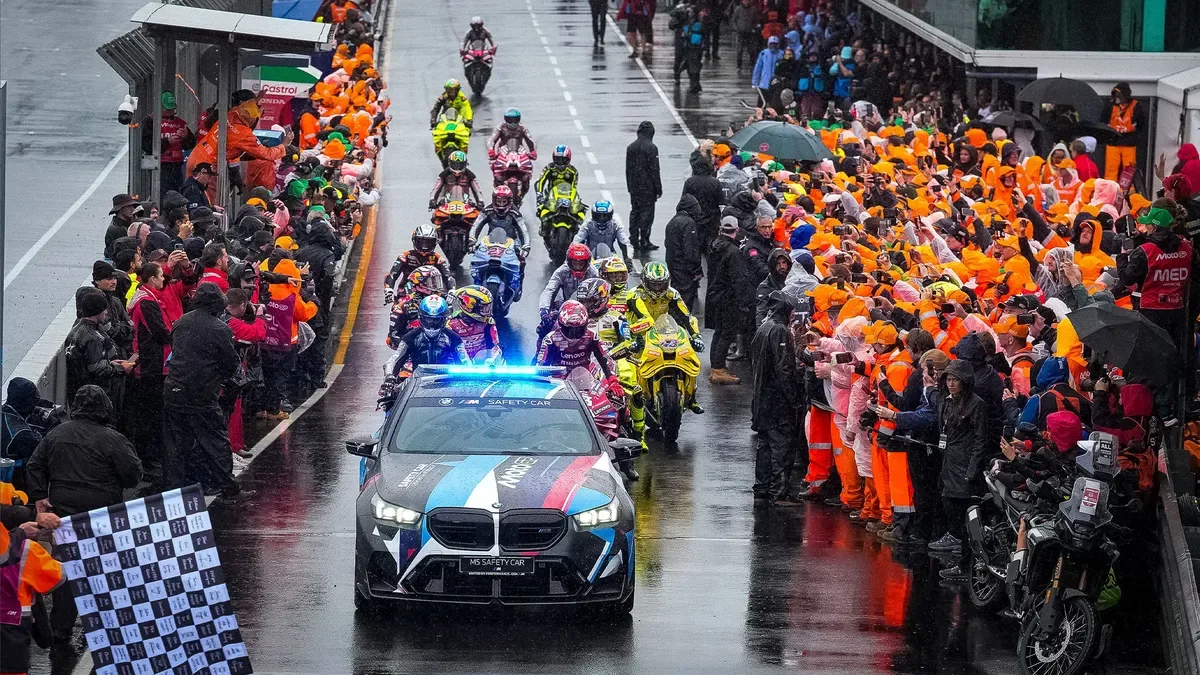 MotoGP riders follow the safety car past spectators during the Phillip Island farewell laps.