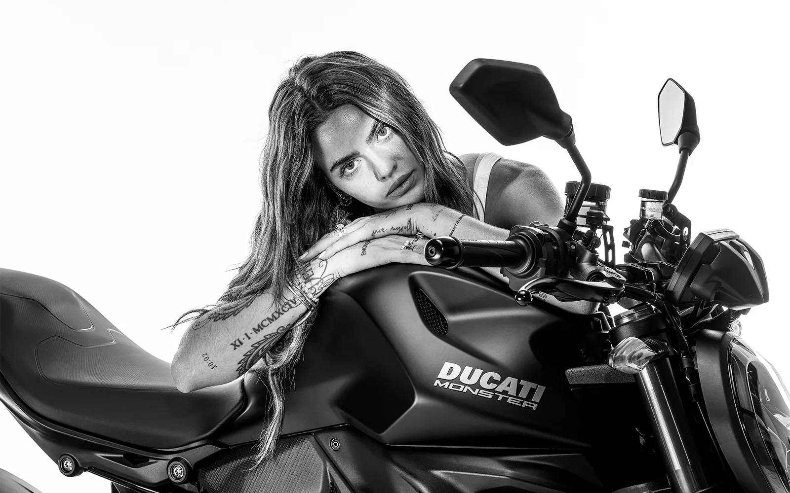 Ducati publicity portrait of a woman leaning beside a black Monster Dark