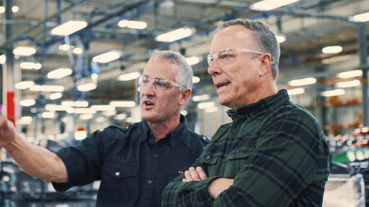 Mike Kennedy speaking with another man inside a motorcycle manufacturing facility