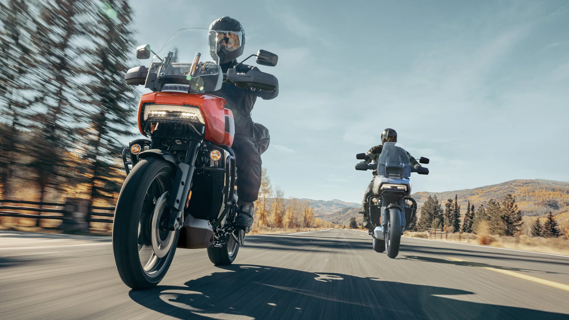 Two riders on Harley-Davidson Pan America motorcycles on a paved road.