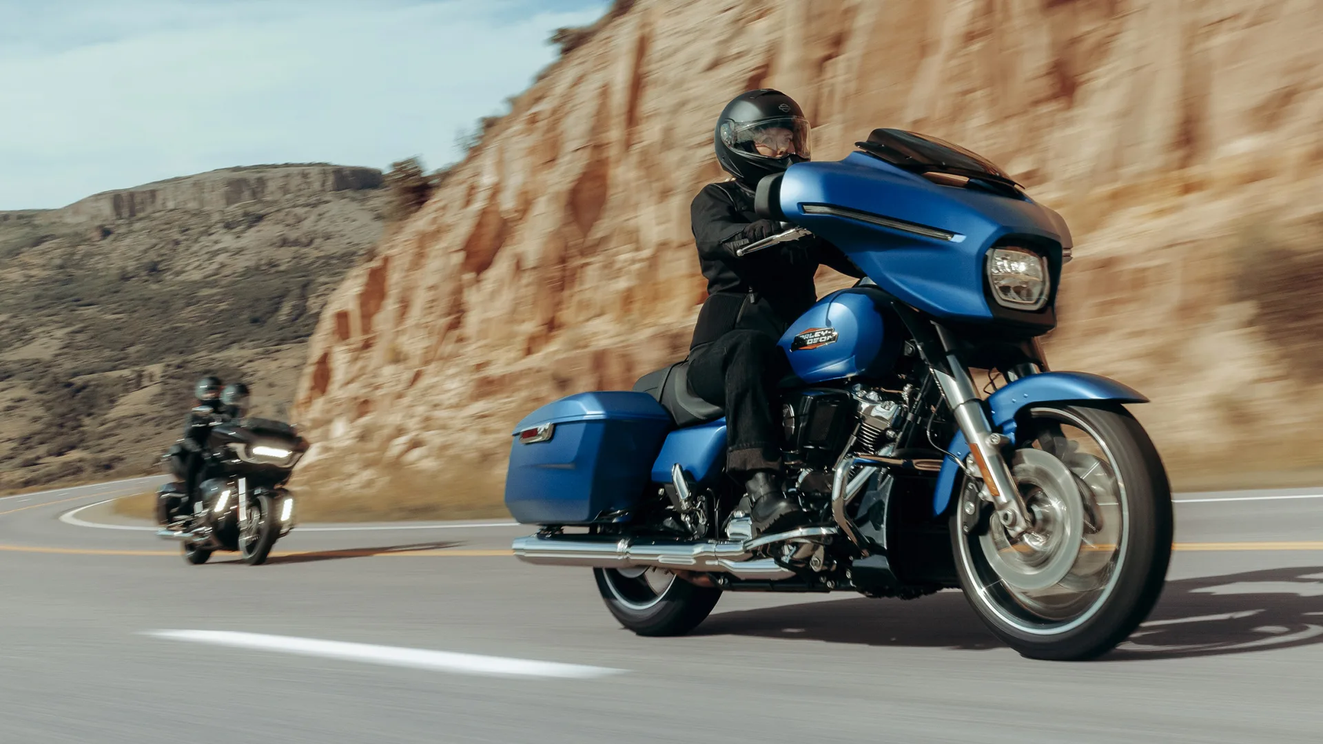 Riders on Harley-Davidson Street Glide motorcycles travelling along a paved road.