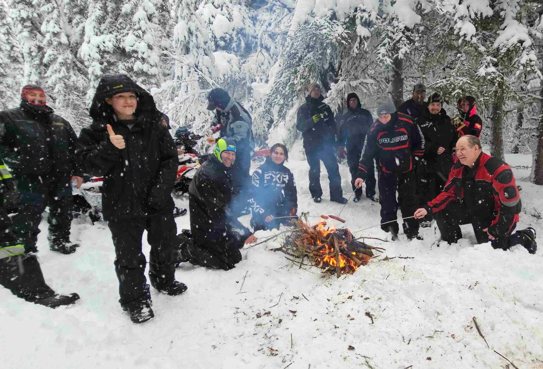Alberta snowmobile club members gathered around a campfire during a winter ride