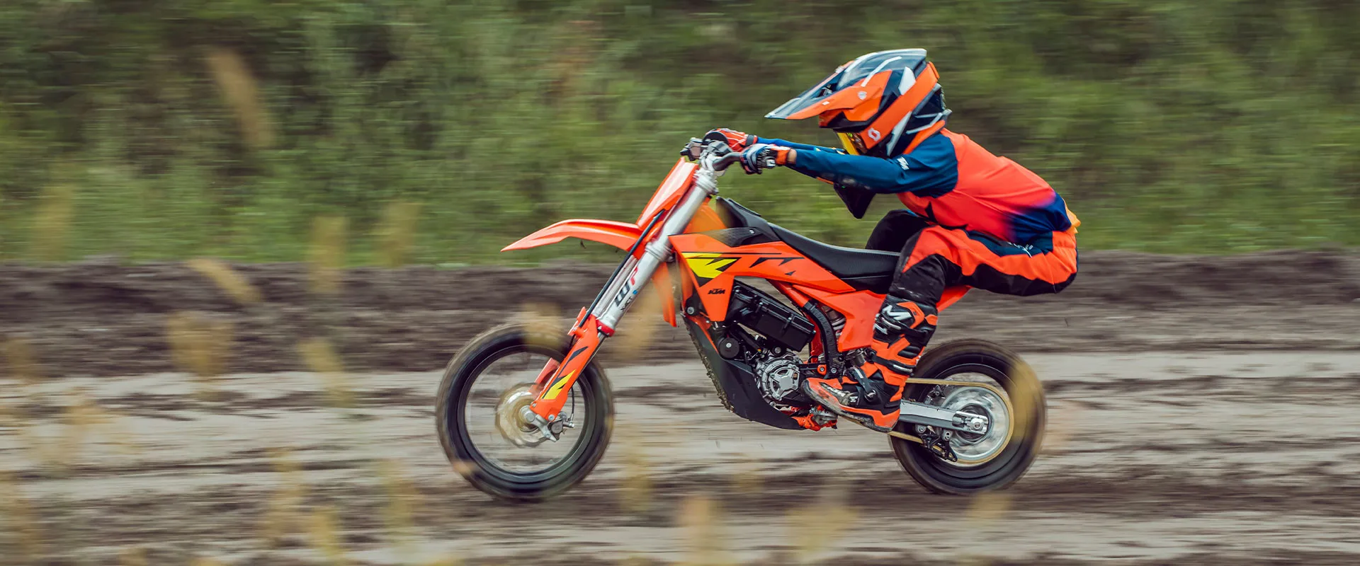 Helmeted young rider riding a KTM SX-E 5 on a dirt track