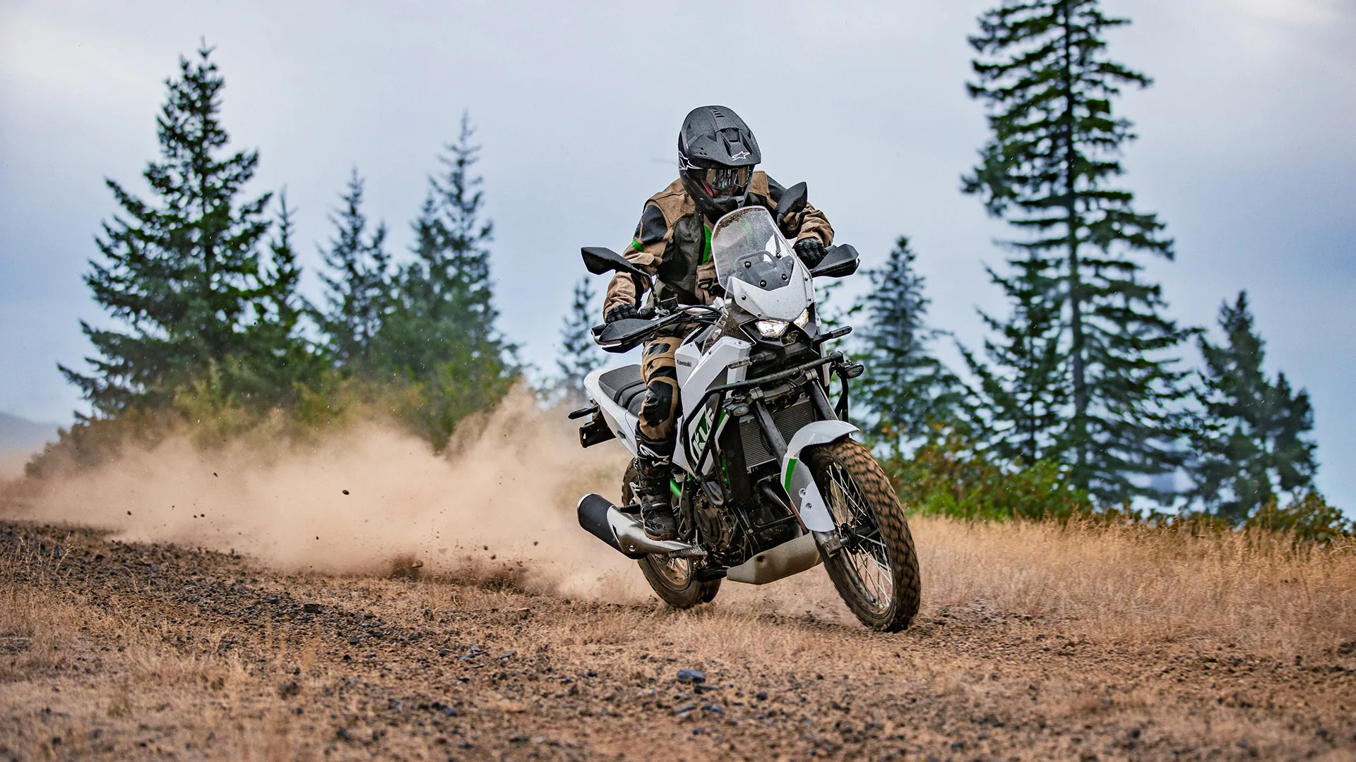 A Kawasaki KLE500 rider turning across loose ground and raising dust.