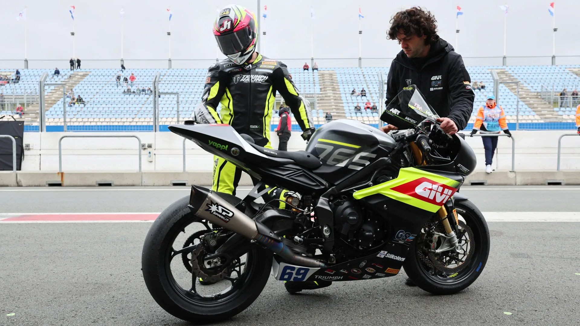 Tom Booth-Amos and team personnel with a 2026 PTR Triumph race motorcycle in the paddock